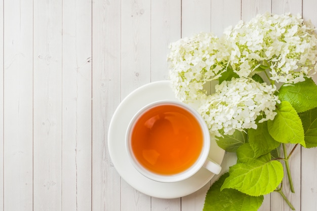 Tazza di tè sul tavolo con fiori. mattina colazione accogliente. copia spazio