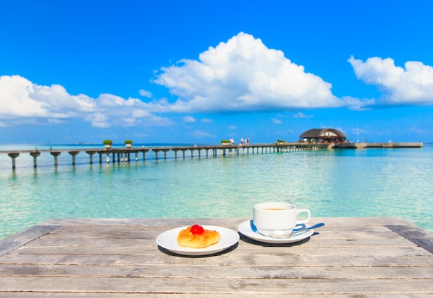 A cup of tea on table with sea at the background