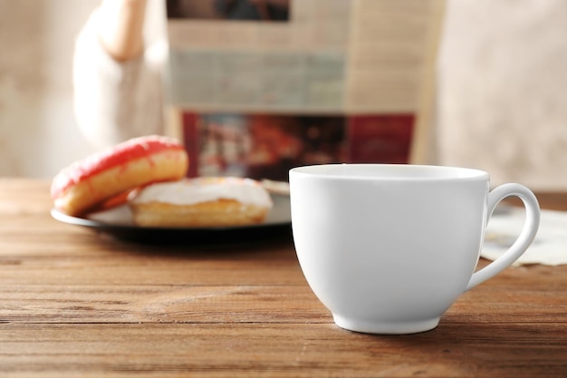 Photo cup of tea and tasty breakfast on table with person reading newspaper on background