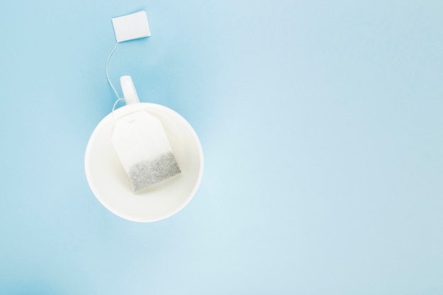 Cup of tea and tea bags on blue background. 