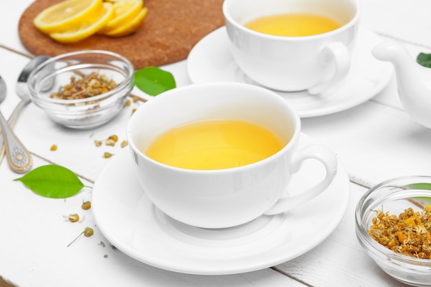 Cup of tea and tea leaves on white wooden table. close up.