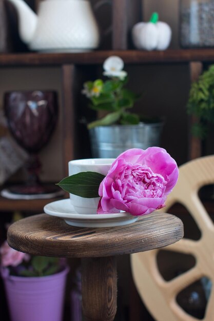 A cup of tea and a teapot with a rose on a wooden background with a wooden wheel The concept of breakfast in the village