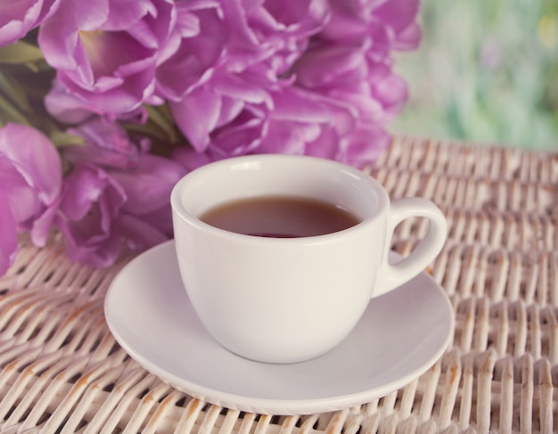 A cup of tea and violet tulips on the table