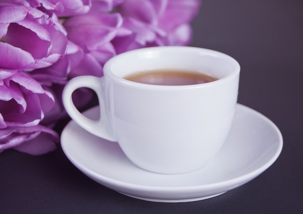 Una tazza di tè e tulipani viola sul tavolo