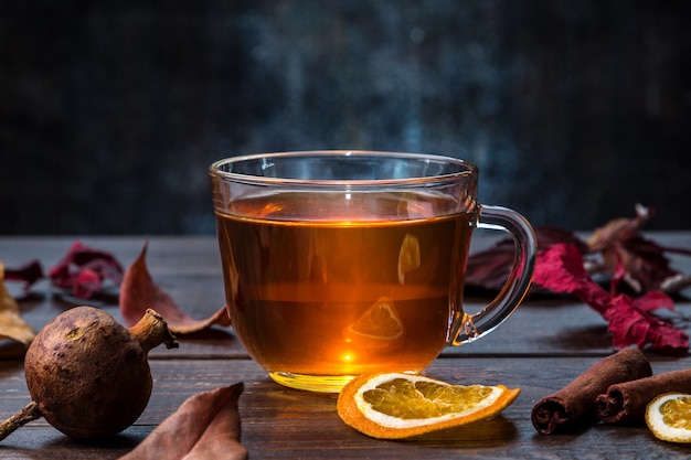 A cup of tea with autumn leaves and dried citrus