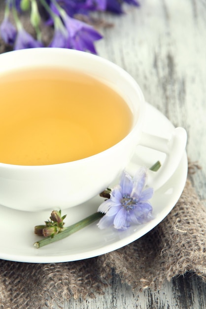 Cup of tea with chicory on wooden background