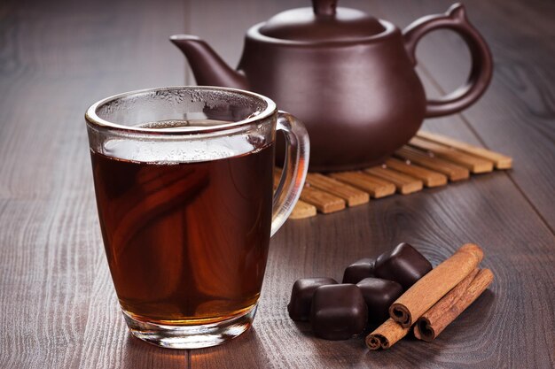 Cup of tea with cinnamon sticks and teapot