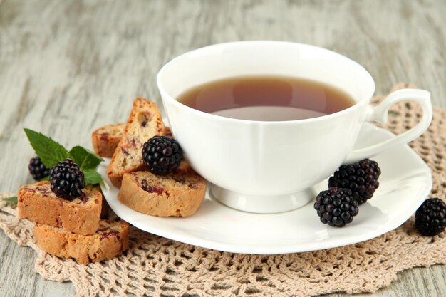 Cup of tea with cookies and blackberry on table closeup