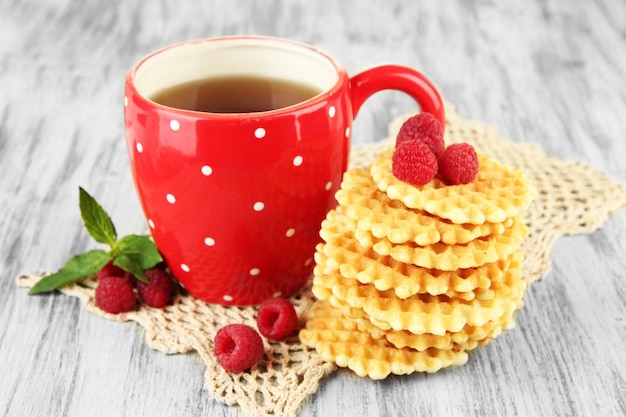 Cup of tea with cookies and raspberries on table closeup