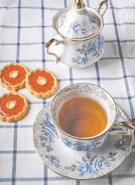 Cup of tea with cookies and sugar-bowl on squared cloth