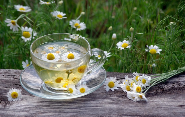 Photo a cup of tea with daisies in the background