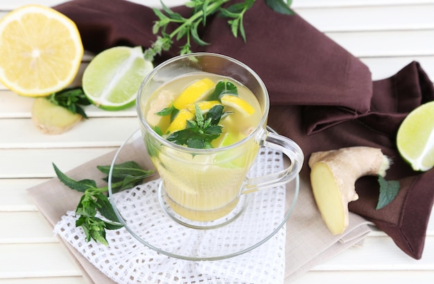 Cup of tea with ginger on napkin on wooden table