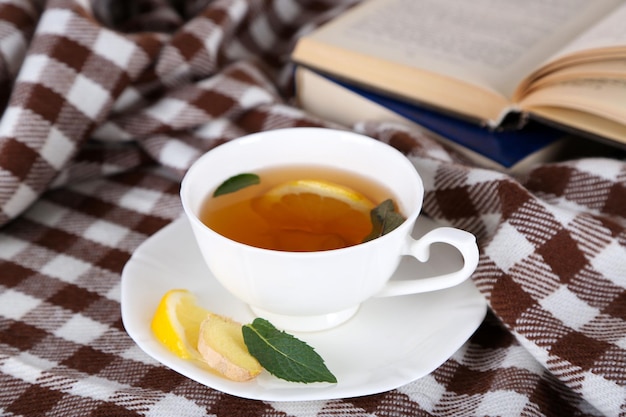 Cup of tea with ginger on plaid with a book