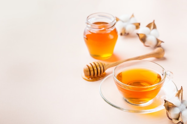 Cup of tea with honey on a trendy pastel pink, apricot background. Copy space