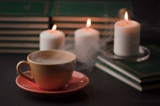 cup of tea with hot smoke and three burning candles on the desk at home power outage