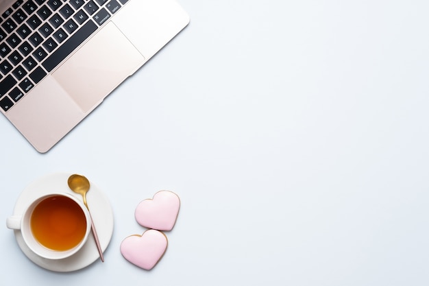 Cup of tea with laptop and pink hearts on a table