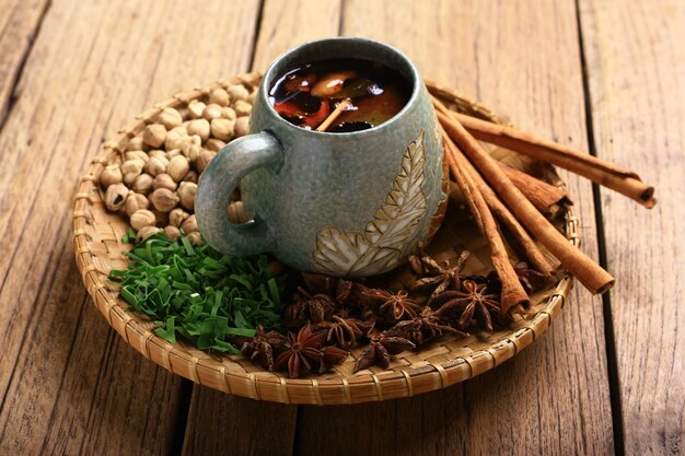 Foto una tazza di tè con sopra una foglia e una ciotola di fagioli su un piatto