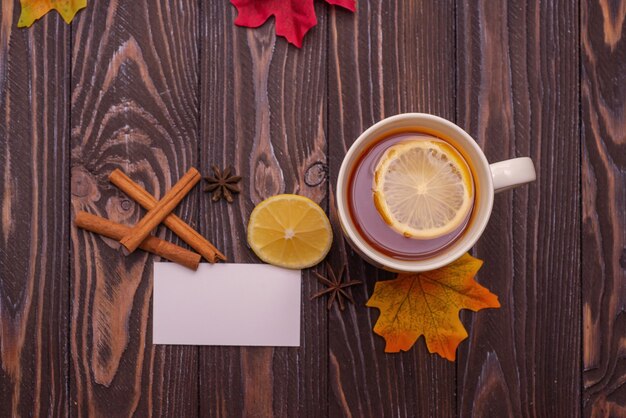 A cup of tea with lemon and cinnamon sticks on a wooden table warm knitted snood autumn mood