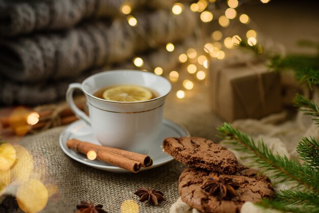 Cup of tea with lemon and cookies close-up with selective focus. festive composition with tea, cookies and garlands.