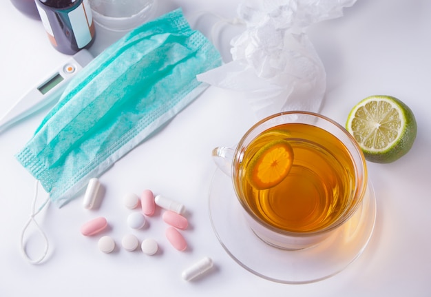 Cup of tea with lemon, thermometer, medicaments and pills. Disease concept. Top view.