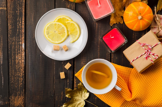 Cup of tea with lemon on wooden dark table with autumn leaves, pumpkins. Autumn decor, fall mood, autumn still life. Fall season concept. thanksgiving and halloween holiday. flat lay, copy space