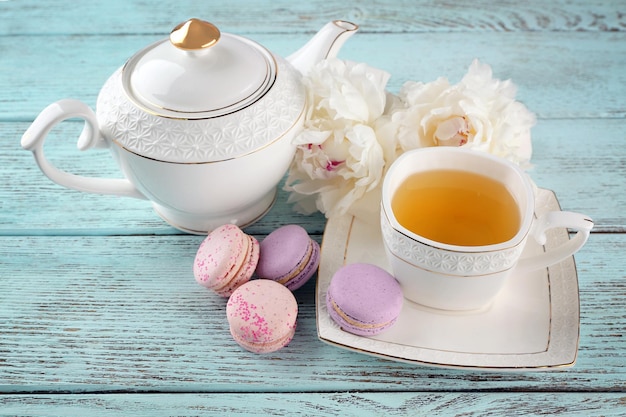 Cup of tea with macaroons and peonies on wooden table