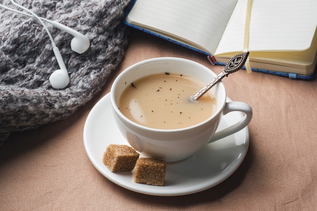 Cup of tea with milk, brown anise sugar and a Notepad.