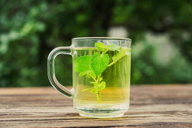 Foto tazza di tè con foglie di menta su tavolo di legno sano tè alla melissa bevanda aromatica biologica naturale in una tazza di vetro