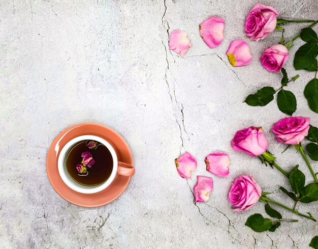 A cup of tea with pink flowers on a concrete background