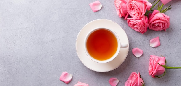 Photo cup of tea with pink rose grey stone background top view copy space