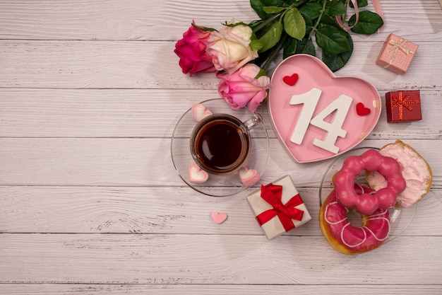 Cup of tea with pink roses on wooden table. Valentine's day concept