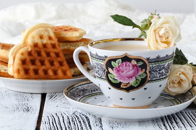 Cup of tea with rose on white wooden table