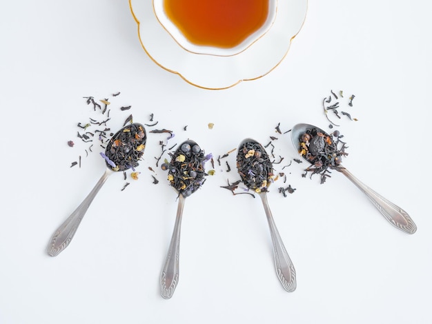 A cup of tea with a saucer and a spoon with dry scattered tea