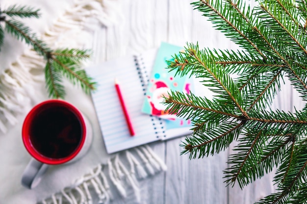 Cup of tea with scarf and notebook on Christmas background