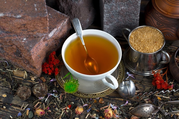 A cup of tea with a spoon next to a cup of tea.