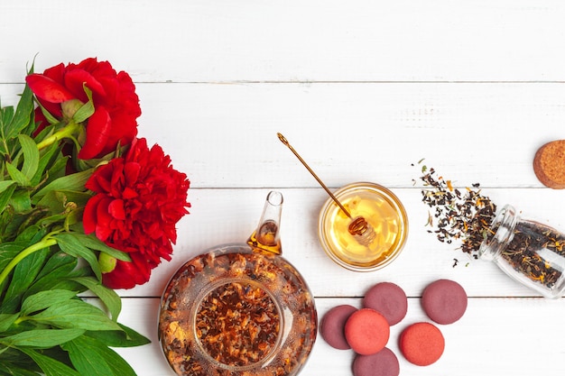 Cup of tea with sweets and flowers on wooden table