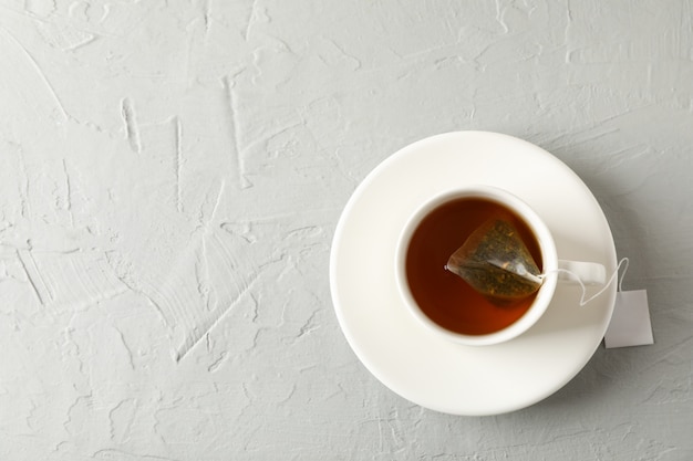 Cup of tea with tea bag on grey, top view