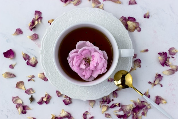 Photo a cup of tea with a tea rose on a white marble background good morning top view