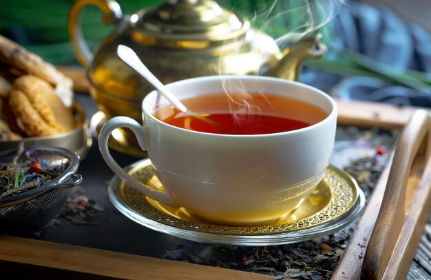 A cup of tea with a teapot and a teapot in the background