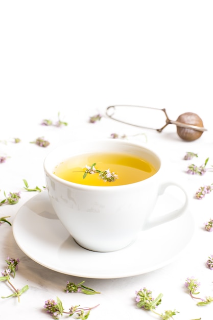 A cup of tea with thyme flowers on a white background. The concept of folk medicine.