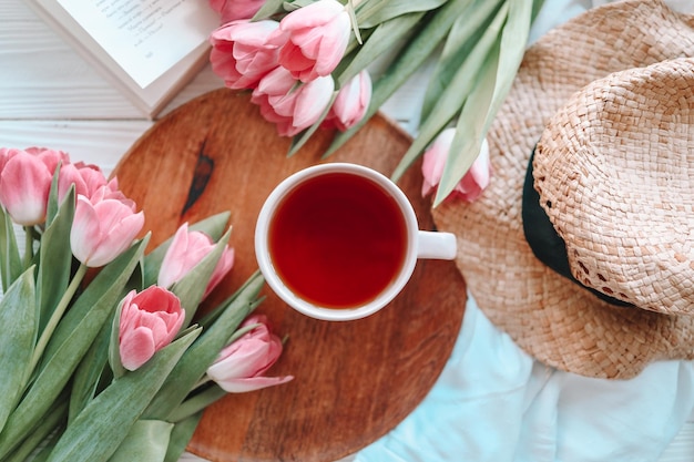 A cup of tea with tulips on rose background