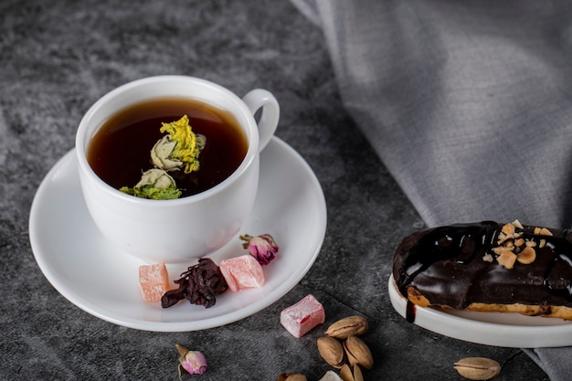 Чашка чая с турецким лукумом и шоколадным эклером. вид сверху