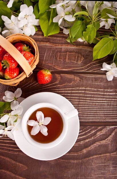 Cup of tea with white apple blossoms on the wooden table