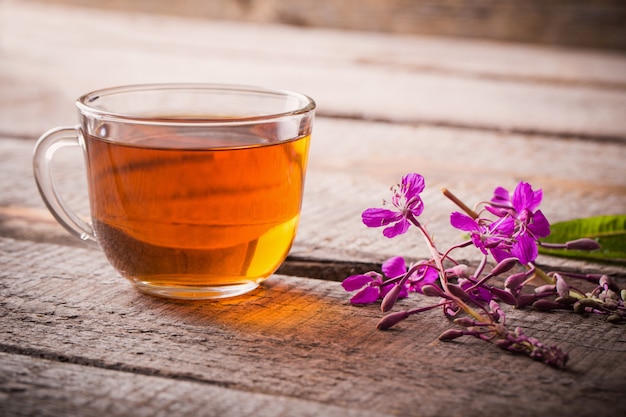 Cup of tea with willow-herb on wooden