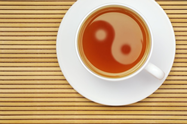 Tazza di tè con il simbolo yin yang su una stuoia di rattan