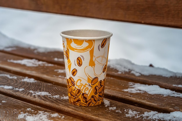 A cup of tea on a wooden bench in cold winter