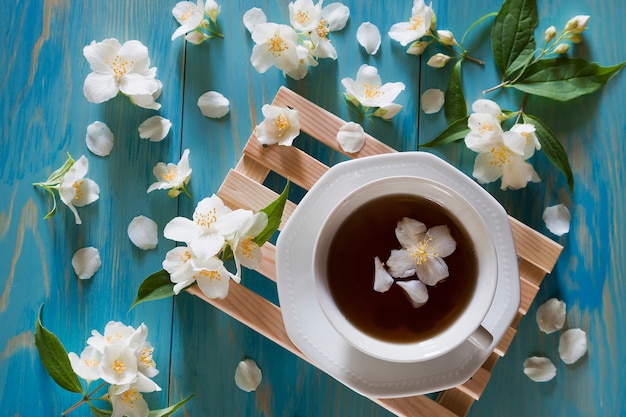  Cup of tea on wooden mini pallet with jasmine flowers. 