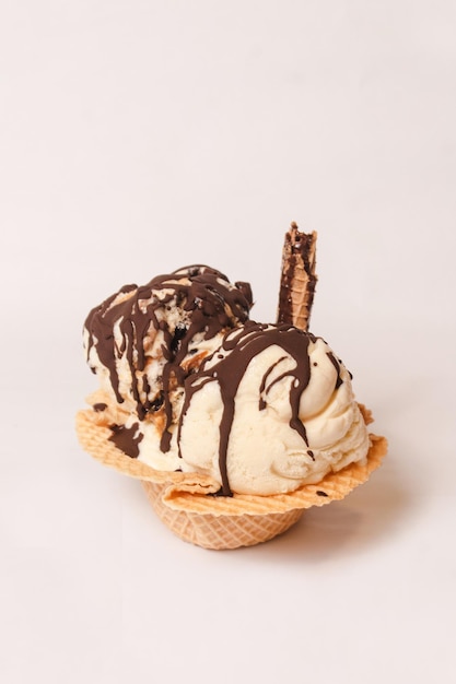 Cup of vanilla ice cream with melted chocolate on a white background