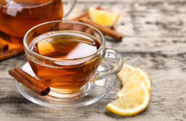 Foto tazza con tè alla cannella caldo aromatico e limone sulla tavola di legno