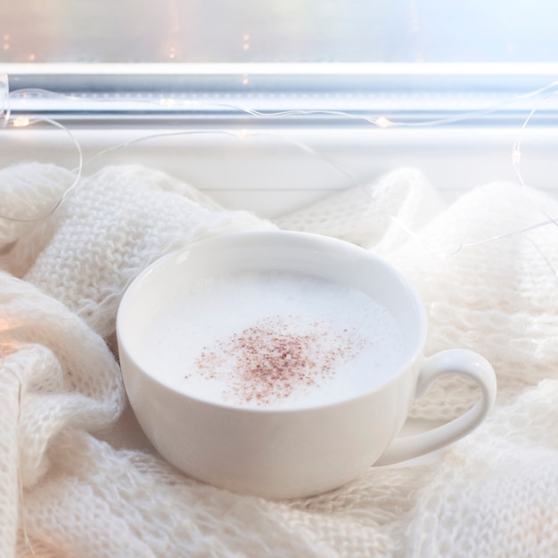 Cup with cappuccino by the window. Winter cozy life style